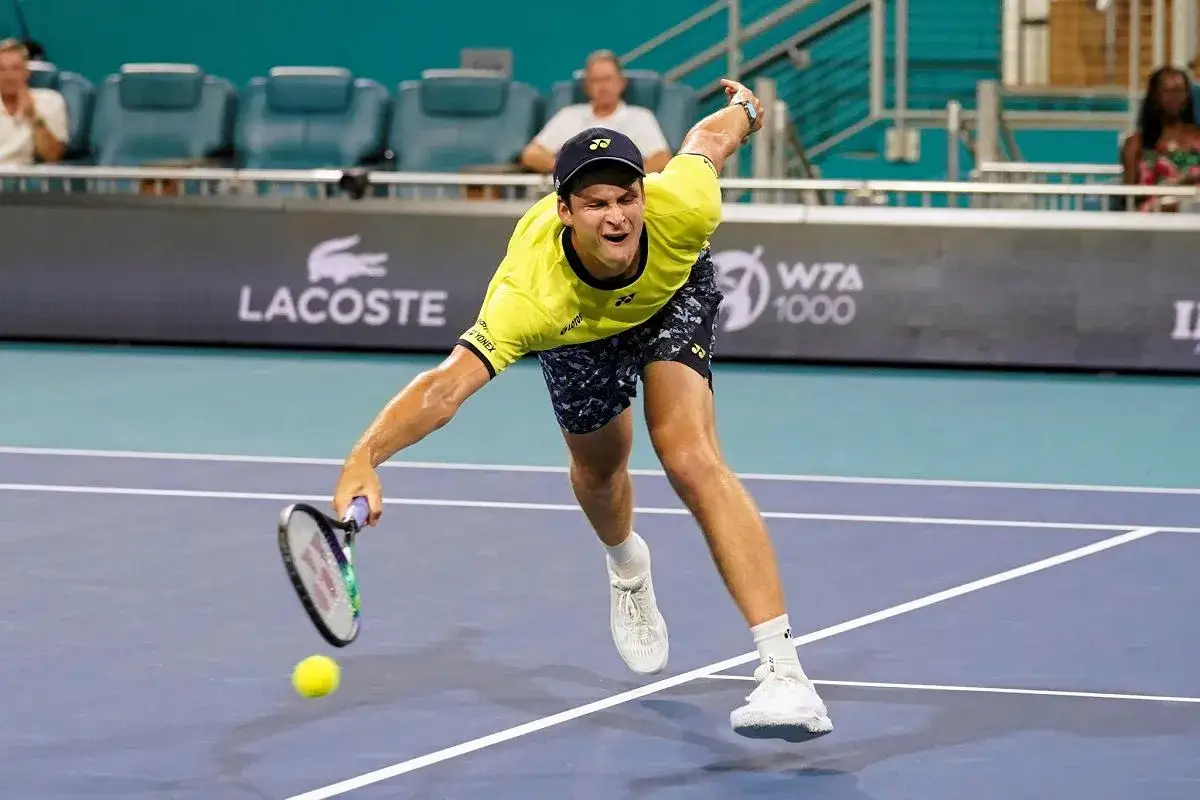 Hubert Hurkacz, ile lat ma Hubert Hurkacz, w akcji na korcie tenisowym, w ż&oacute;łtej koszulce i granatowych spodenkach, podczas meczu WTA 1000.