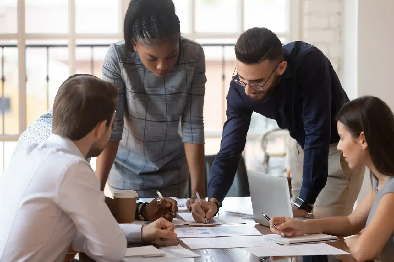 Équipe concentrée sur la résolution de problèmes, analysant des documents et collaborant autour d'une table.