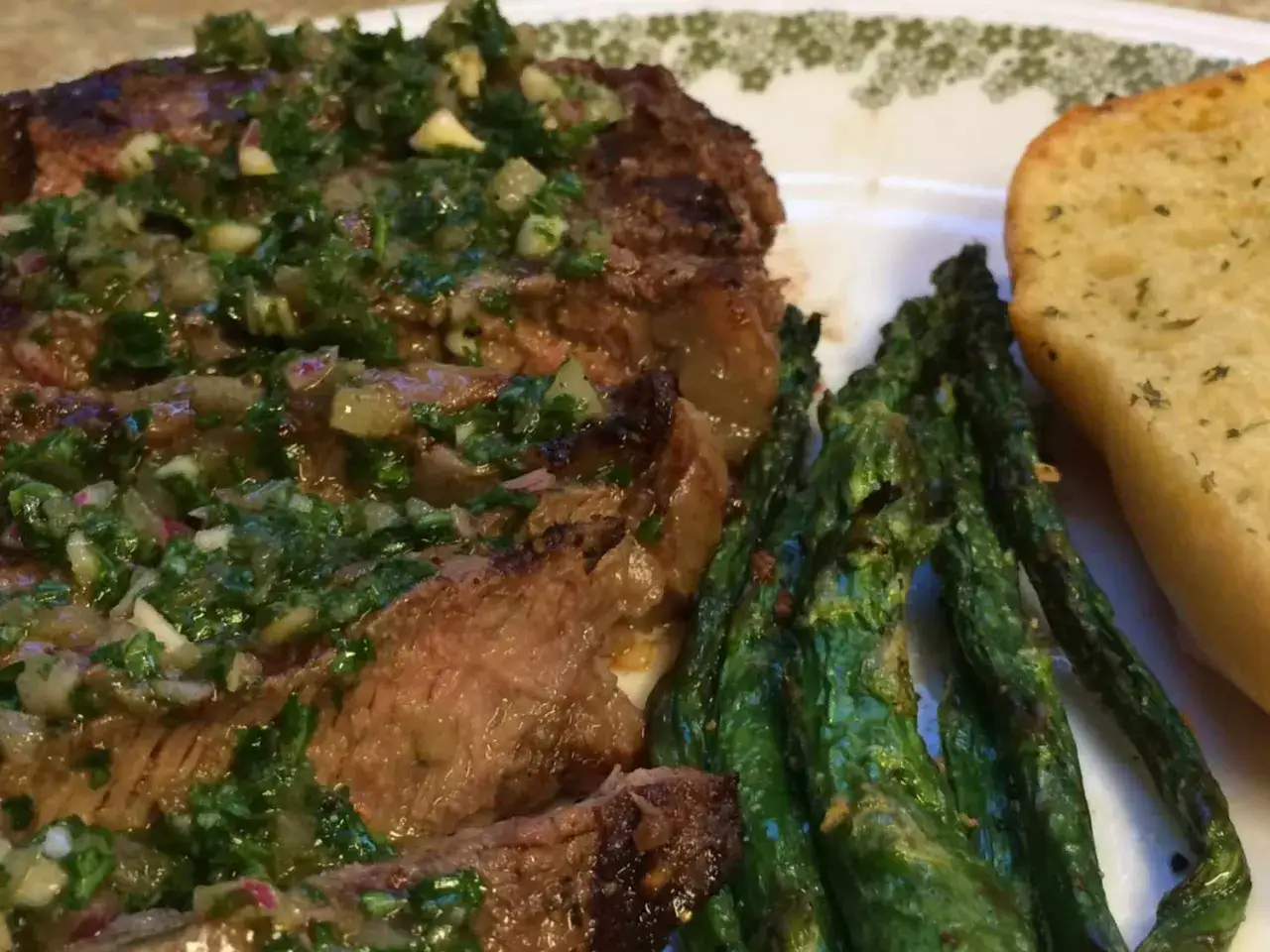Saftiges Steak mit frischem Chimichurri-Rezept, dazu gegrillter Spargel und Knoblauchbrot.