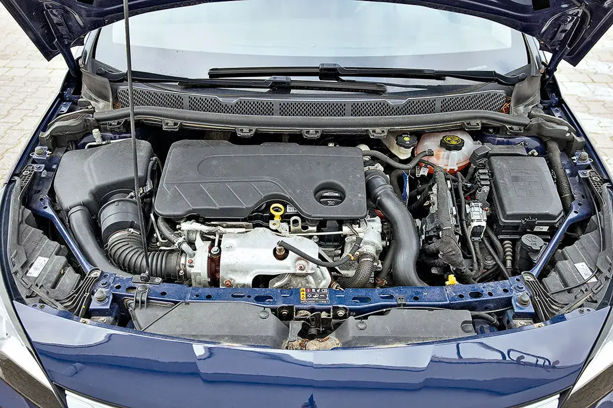 Motorraum eines blauen Autos. Der Motor ist sichtbar, mit vielen Kabeln und Schläuchen. Die Bedeutung von CDTI ist hier nicht ersichtlich.