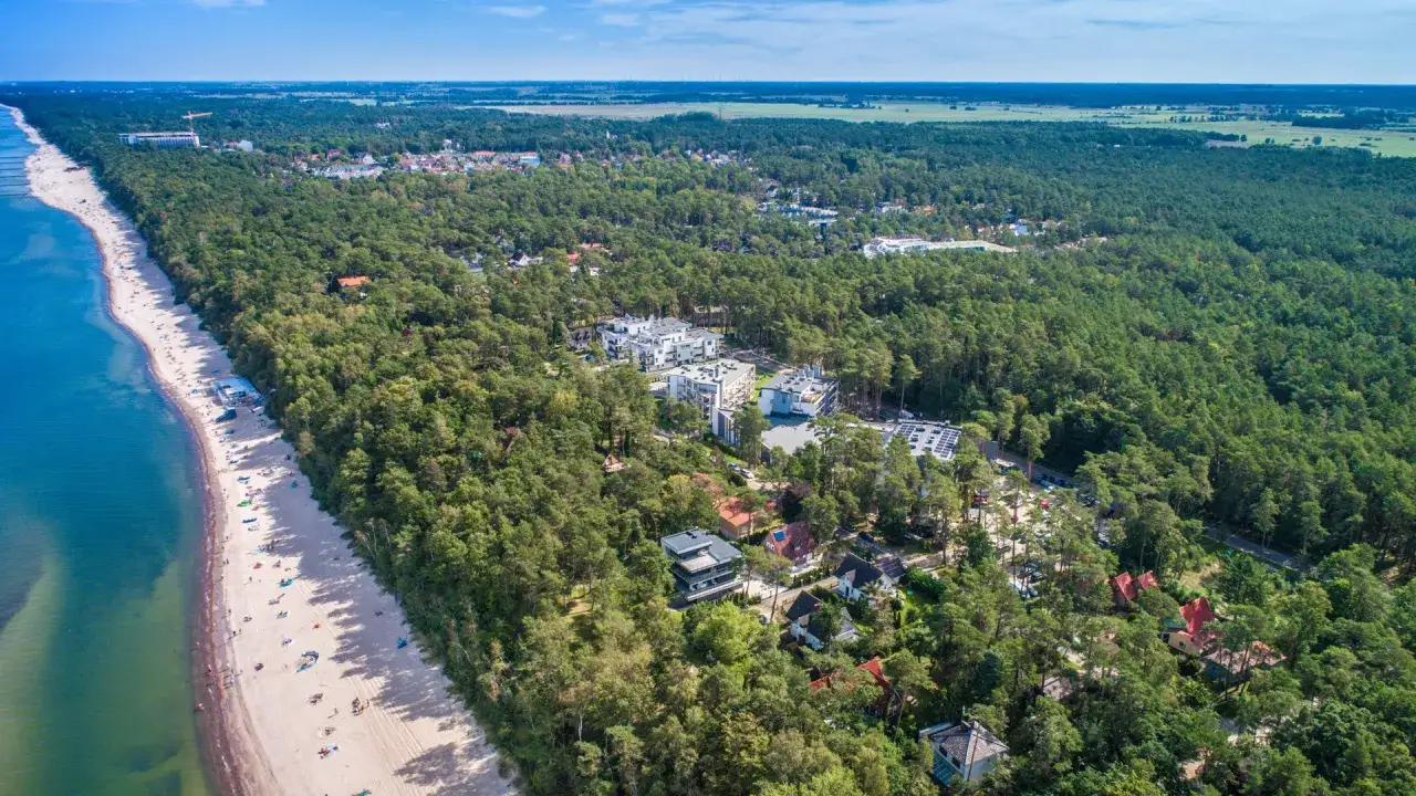 Piękna plaża i sosnowy las na Pomorzu Zachodnim. Atrakcje turystyczne w otoczeniu natury, nowoczesne budynki i domy.