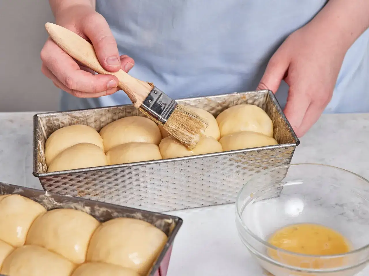 H&auml;nde bestreichen mit einem Pinsel das Brot mit Wasser f&uuml;r einen sch&ouml;nen Glanz.