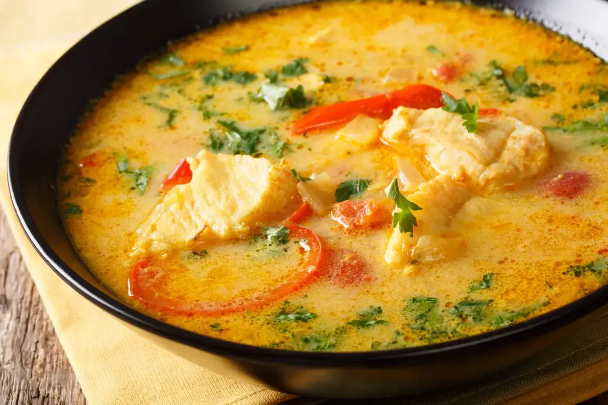 Un plat de poisson crémeux avec des morceaux de poisson, des tomates et des herbes, le tout nappé d'une sauce onctueuse à la sauce noilly prat.
