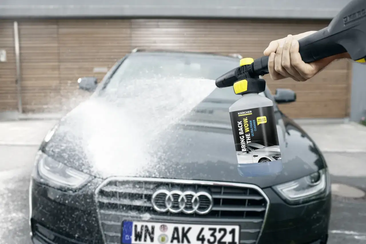 Kärcher skumtvätt appliceras på en mörk Audi. En hand håller högtryckstvätten med skumbehållaren.