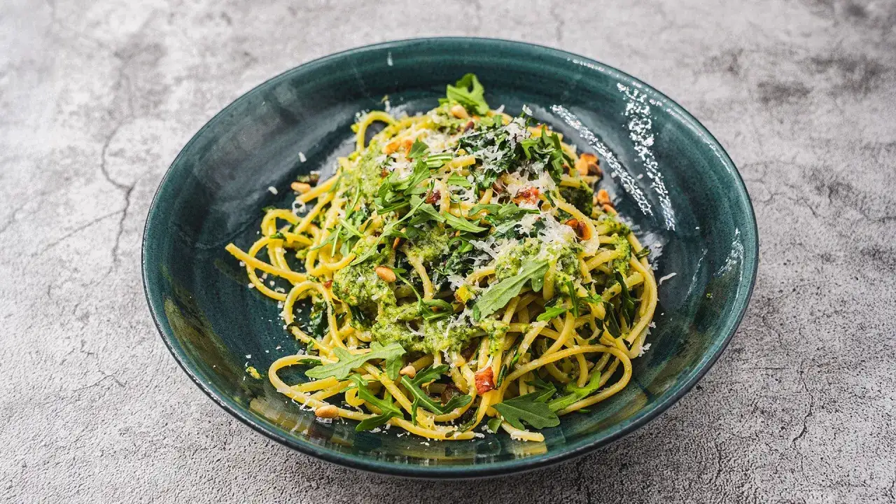 Spaghetti mit frischem Rucola Pesto, Pinienkernen und Parmesan.