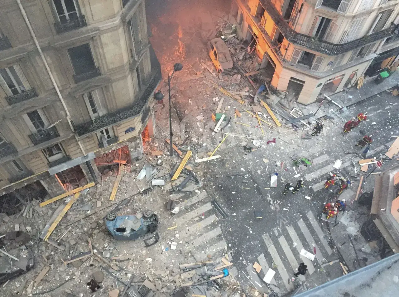 D&eacute;g&acirc;ts consid&eacute;rables suite &agrave; une explosion de gaz &agrave; Paris. Des d&eacute;bris jonchent la rue, une voiture est renvers&eacute;e. Les pompiers interviennent sur les lieux.