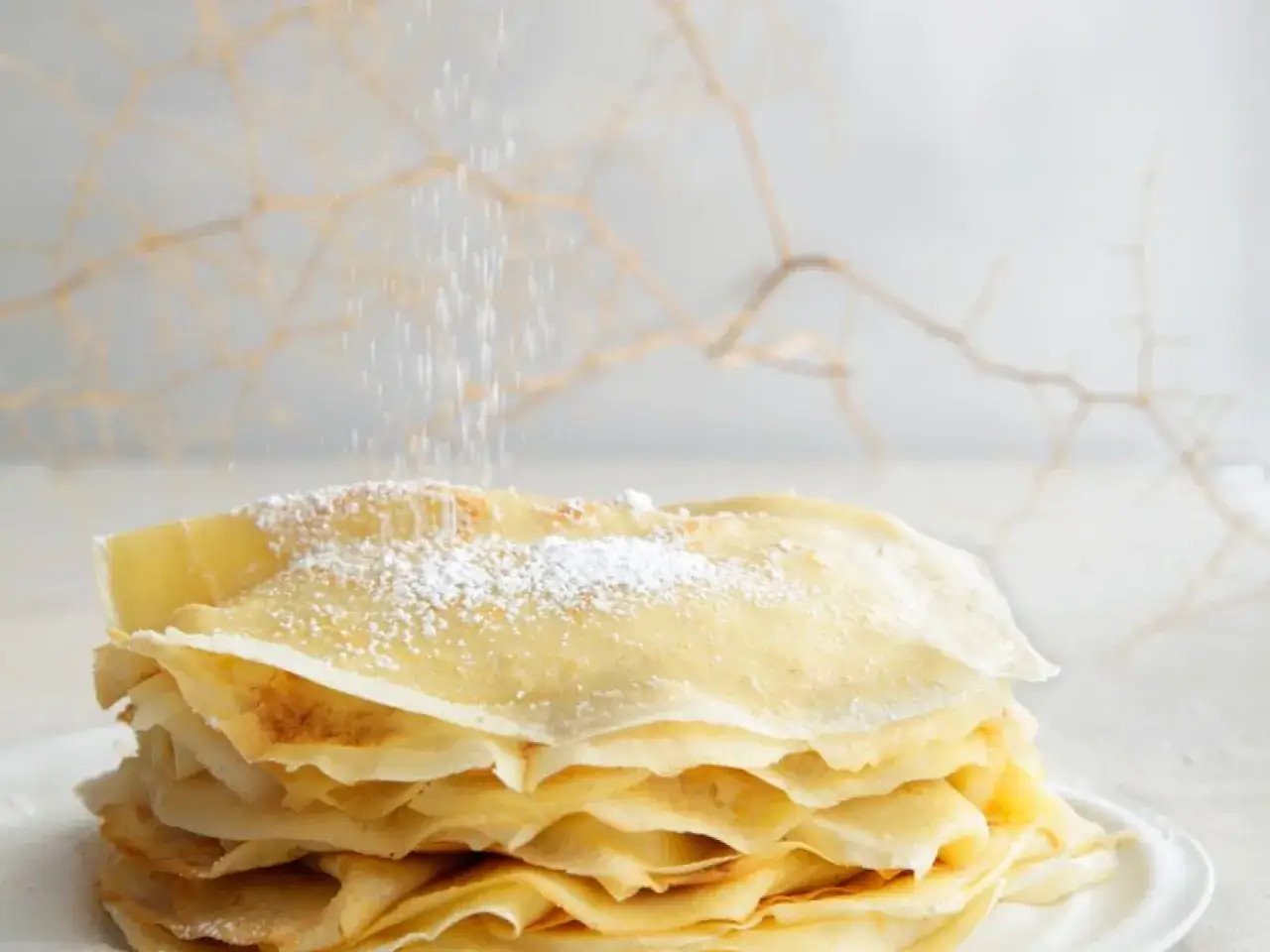 Ein Stapel frisch gebackener Eierkuchen wird mit Puderzucker bestäubt. Ein köstliches Rezept für süße Momente.