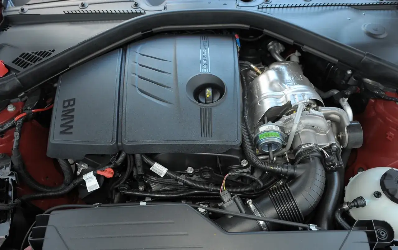 Silnik TwinPower Turbo w BMW 118i. Widoczny jest czarny plastikowy dekiel z logo BMW i napisem