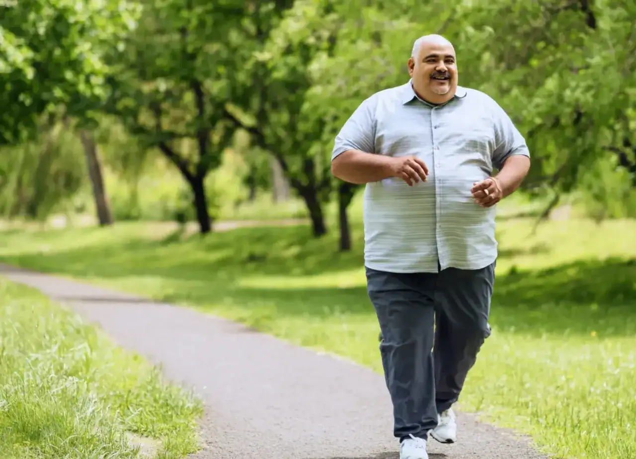 En man njuter av en promenad i parken, bränner kalorier och ler.