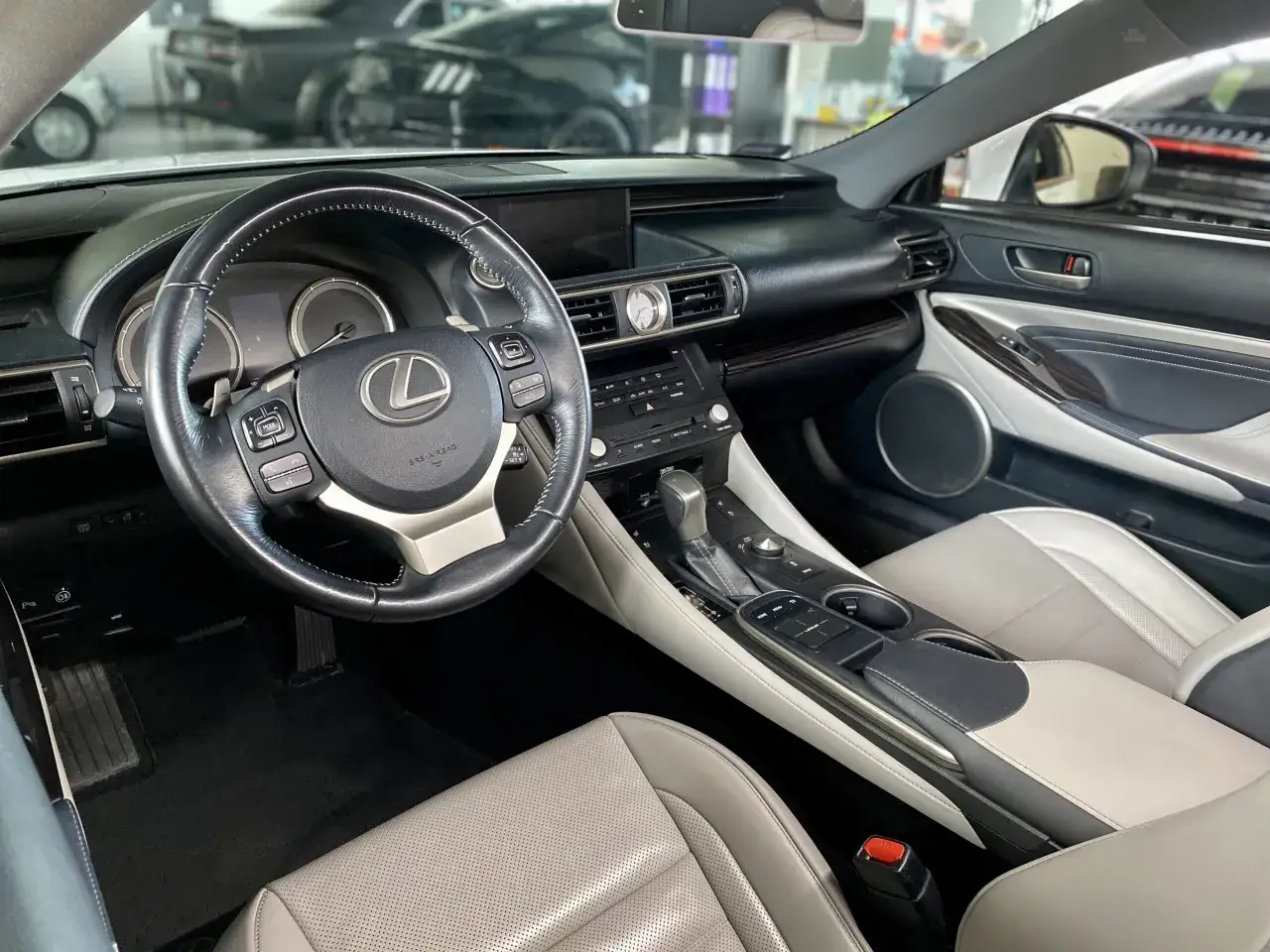 Wnętrze Lexus RC 350 z czarną kierownicą, jasnymi skórzanymi fotelami i konsolą środkową.