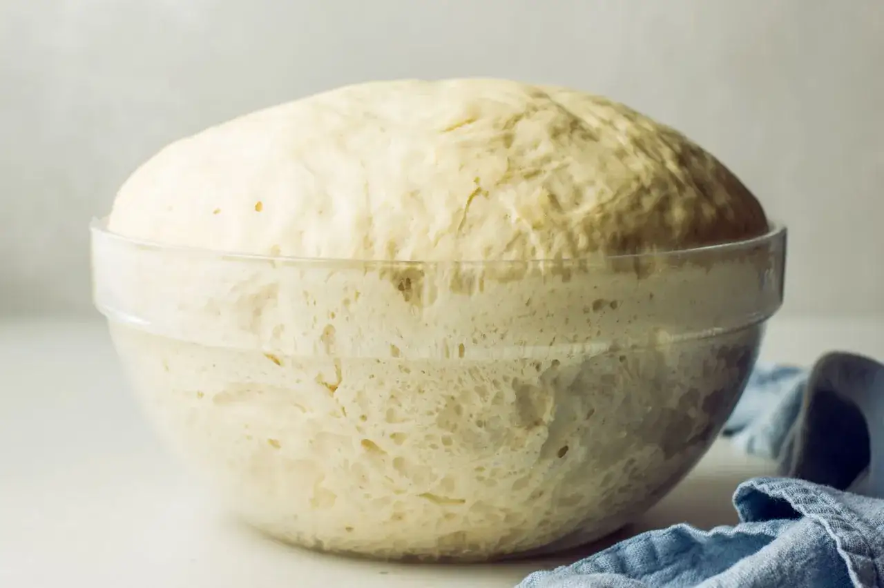 P&acirc;te lev&eacute;e dans un bol en verre, montrant la diff&eacute;rence entre levure chimique et levure boulang&egrave;re. La p&acirc;te a doubl&eacute; de volume.