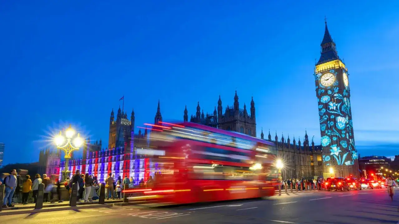 Wieczorny Londyn: Big Ben z projekcją, czerwony autobus w ruchu, tłum ludzi. Darmowe atrakcje Londyn zachwycają!