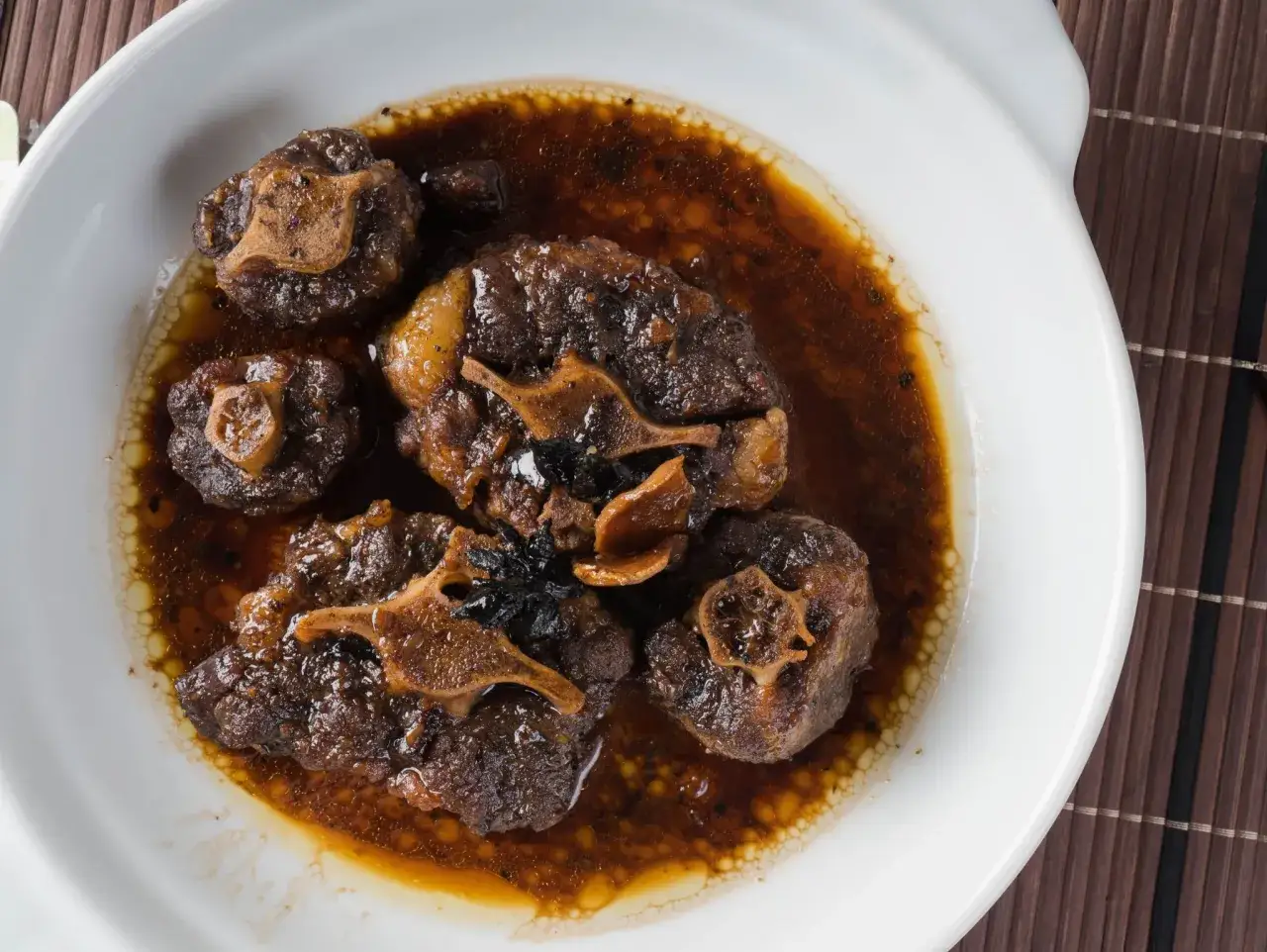 Rabo de toro estofado en una rica salsa oscura, servido en un plato blanco.