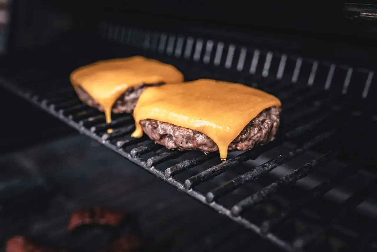 Zwei saftige Burger-Patties auf dem Grill, mit leckerem cheddar schmelzen. Der Käse tropft verführerisch herunter.