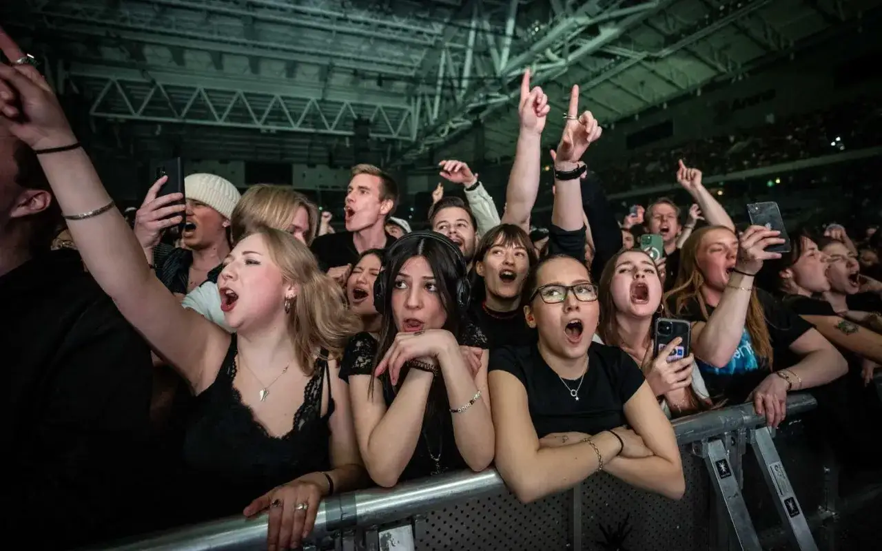 Publiken jublar och sjunger med under en **Tele2 Arena konsert**. Många har händerna i luften och telefoner för att filma.
