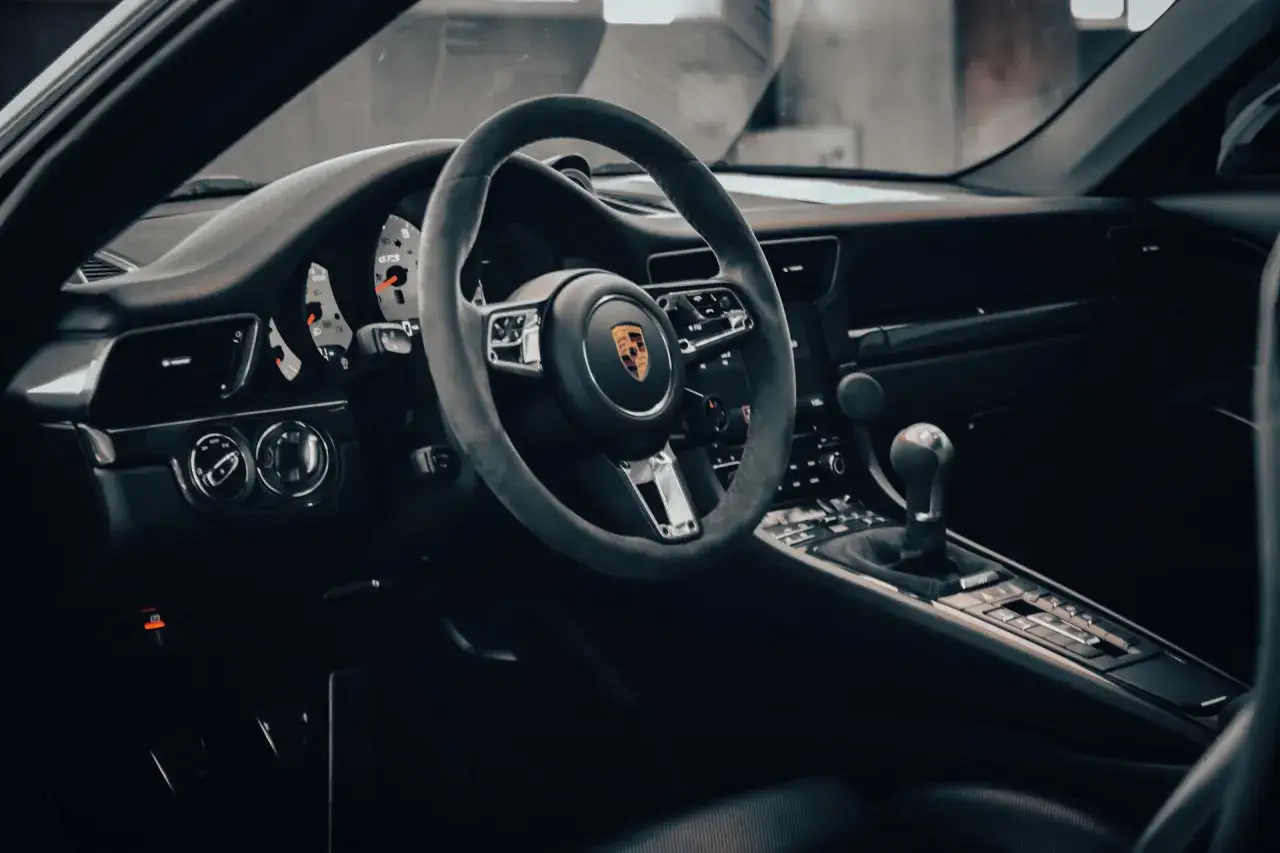 Der porsche 911 innenraum zeigt ein lederbezogenes Lenkrad, das Armaturenbrett mit Tachometer und Schaltknauf.