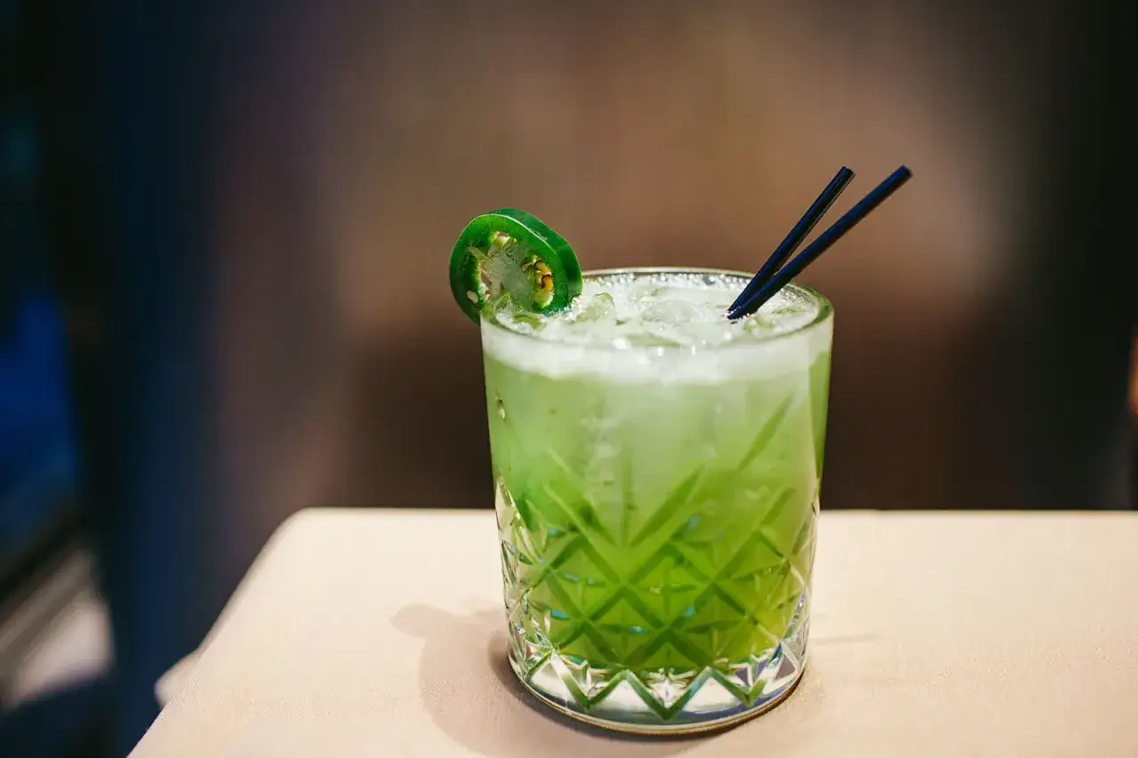 Zielony, orzeźwiający drink z plasterkiem papryczki jalapeno i dwoma czarnymi słomkami. Idealny przykład najprostszych drinków na upalne dni.