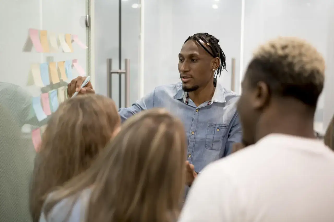 A man writes on sticky notes on a glass wall, illustrating how the Peter Principle refers to employees being promoted to their level of incompetence.