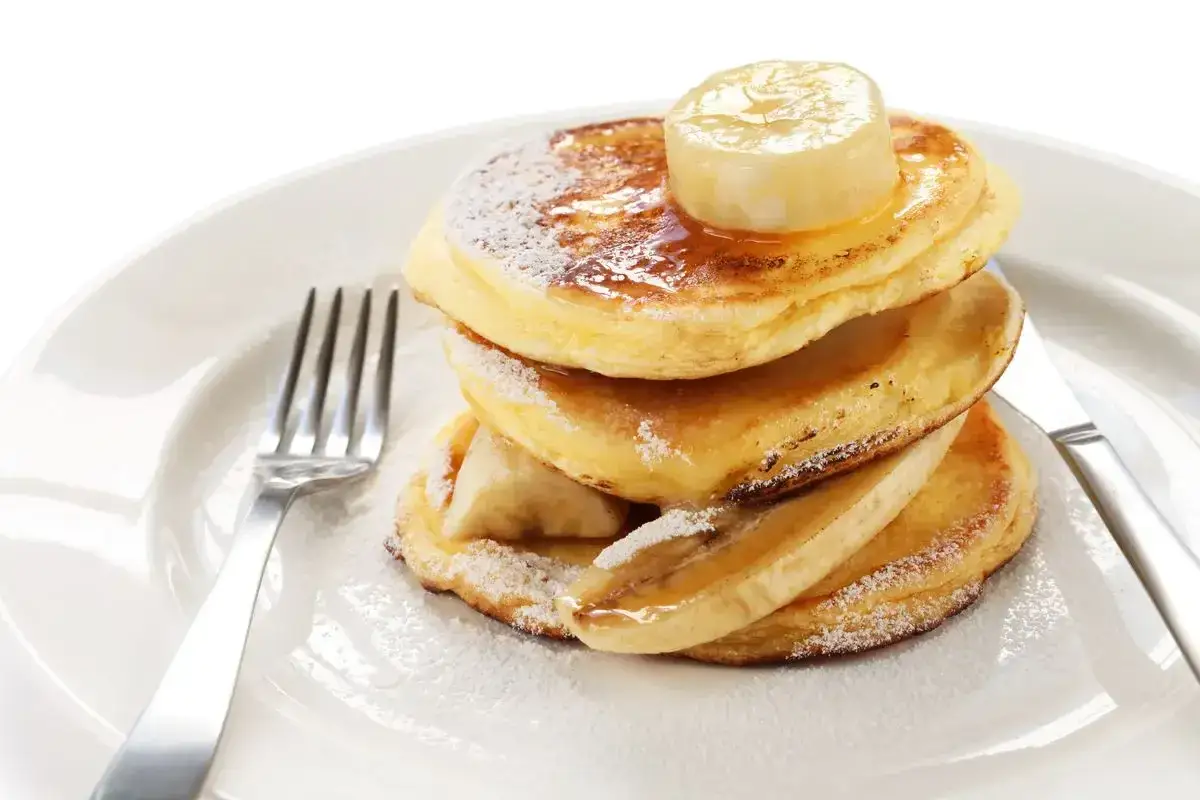 Pancake con albumi, dolci e soffici, guarniti con fette di banana e sciroppo d'acero.