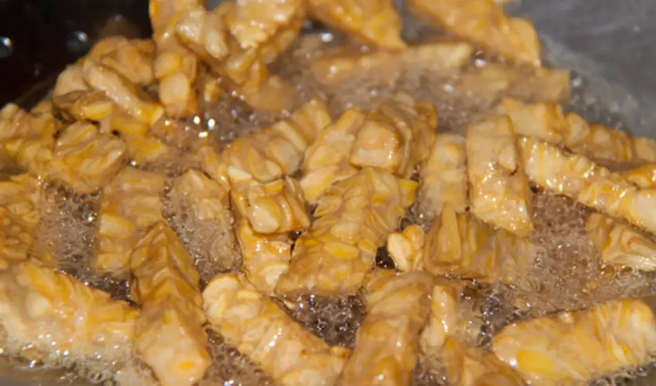 Frittierte indonesische Sojabohnen speise, auch bekannt als Tempeh, brutzeln in hei&szlig;em &Ouml;l und werden goldbraun.