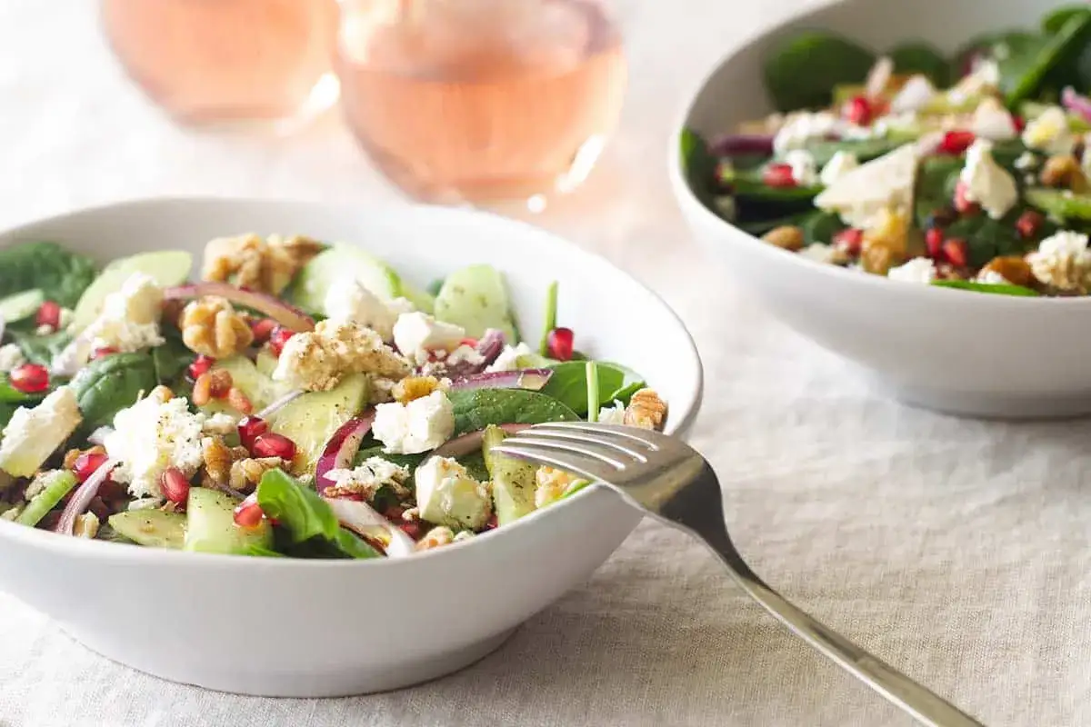 En fräsch grekisk sallad med fetaost, gurka, rödlök och granatäpple, perfekt till ett glas rosévin.