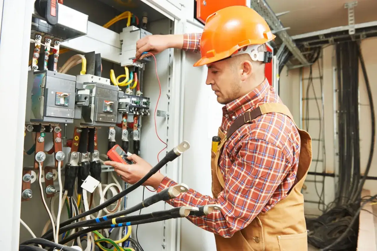 Doświadczony elektryk wysokich napięć sprawdza instalację elektryczną za pomocą miernika.
