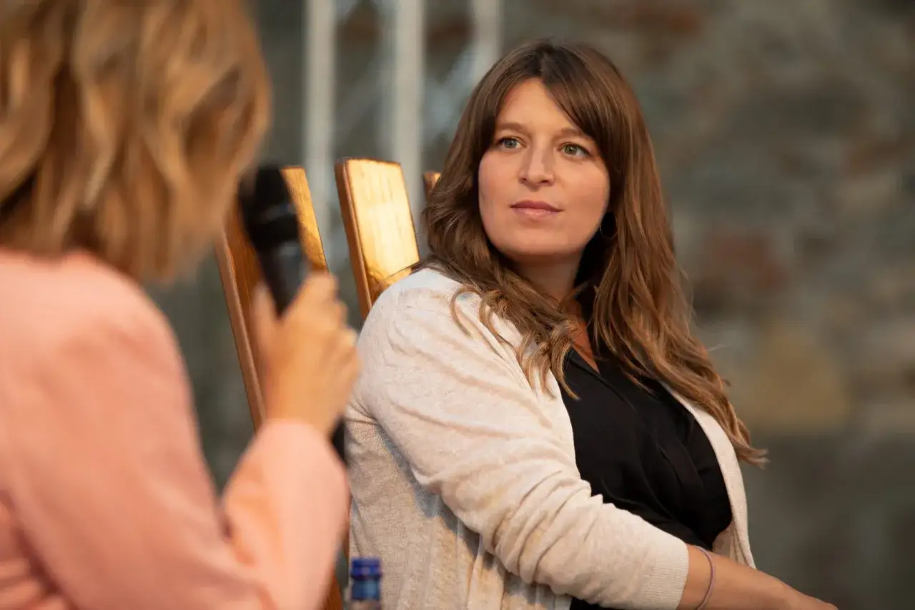 Martina Carone, con i suoi capelli castani mossi, ascolta attentamente durante un'intervista.