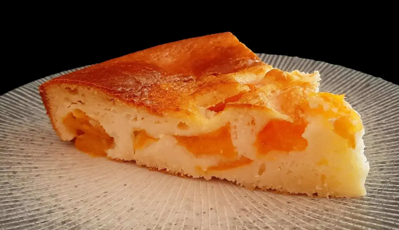 Tranche de clafoutis abricot sans gluten, dor&eacute; et moelleux, aux morceaux d'abricots fondants.