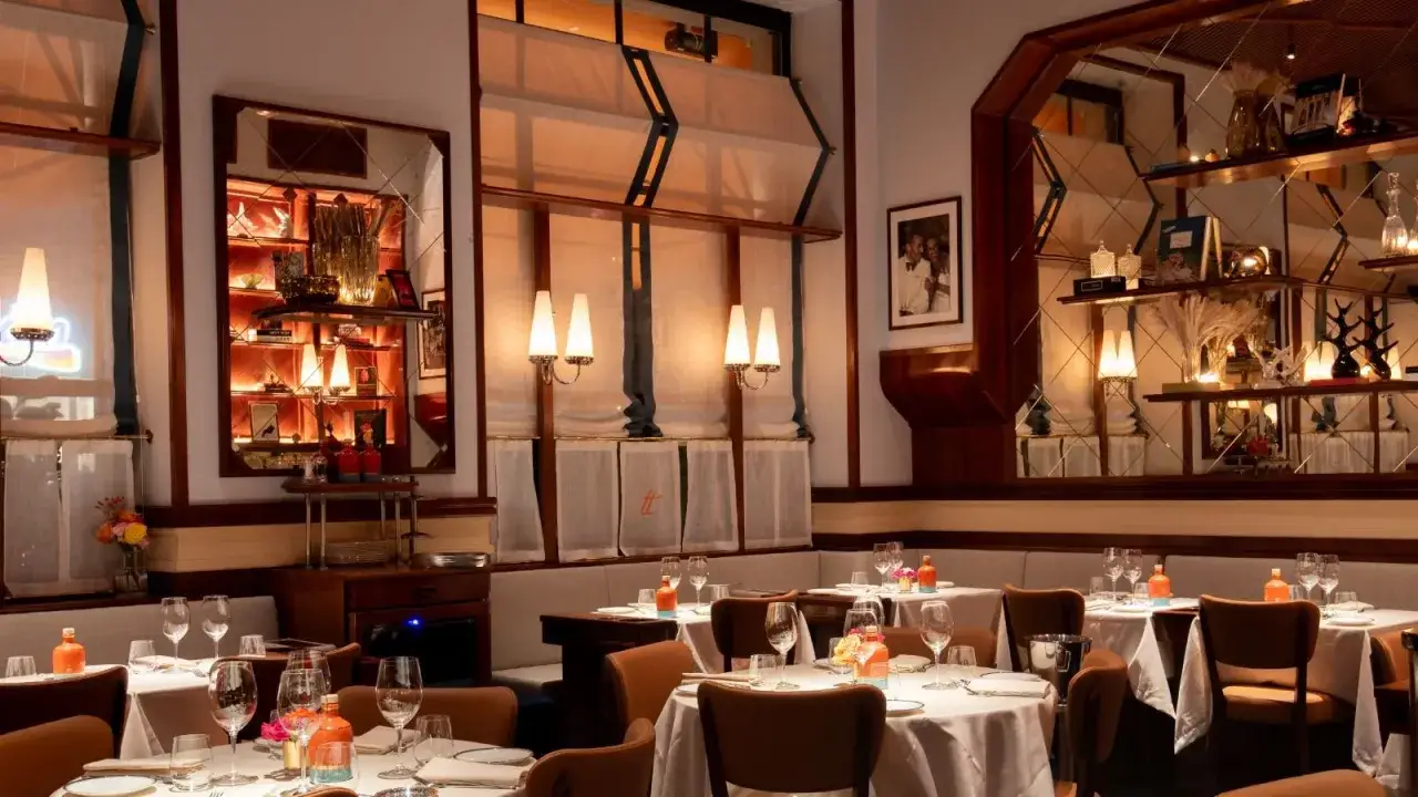 Tavoli apparecchiati in un ambiente elegante, perfetto per scoprire i migliori ristoranti Milano. Luci soffuse e dettagli raffinati creano un'atmosfera accogliente.