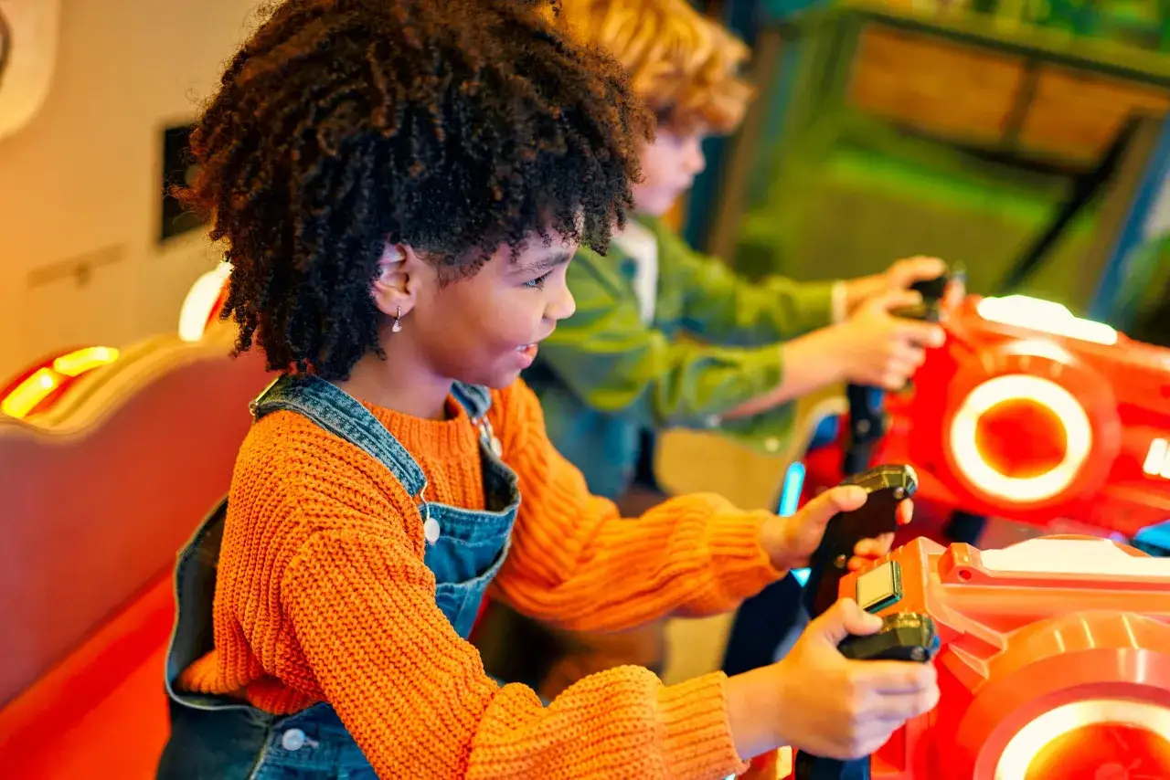 Bambini si divertono con giochi per feste di compleanno al chiuso, impugnando pistole luminose in un'ambientazione colorata.