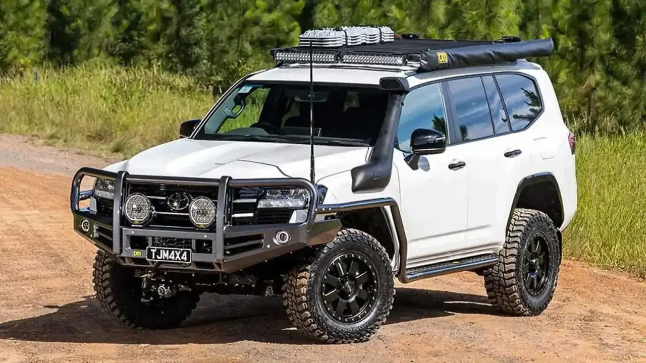Biały Land Cruiser 300 z orurowaniem, wyciągarką, snorkel'em i bagażnikiem dachowym gotowy na off-road.
