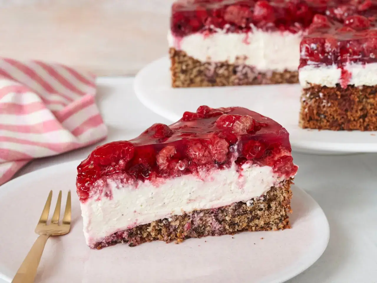 Ein St&uuml;ck Himbeer Mascarpone Torte mit cremigem Frischk&auml;se, fruchtiger Himbeerschicht und nussigem Boden.