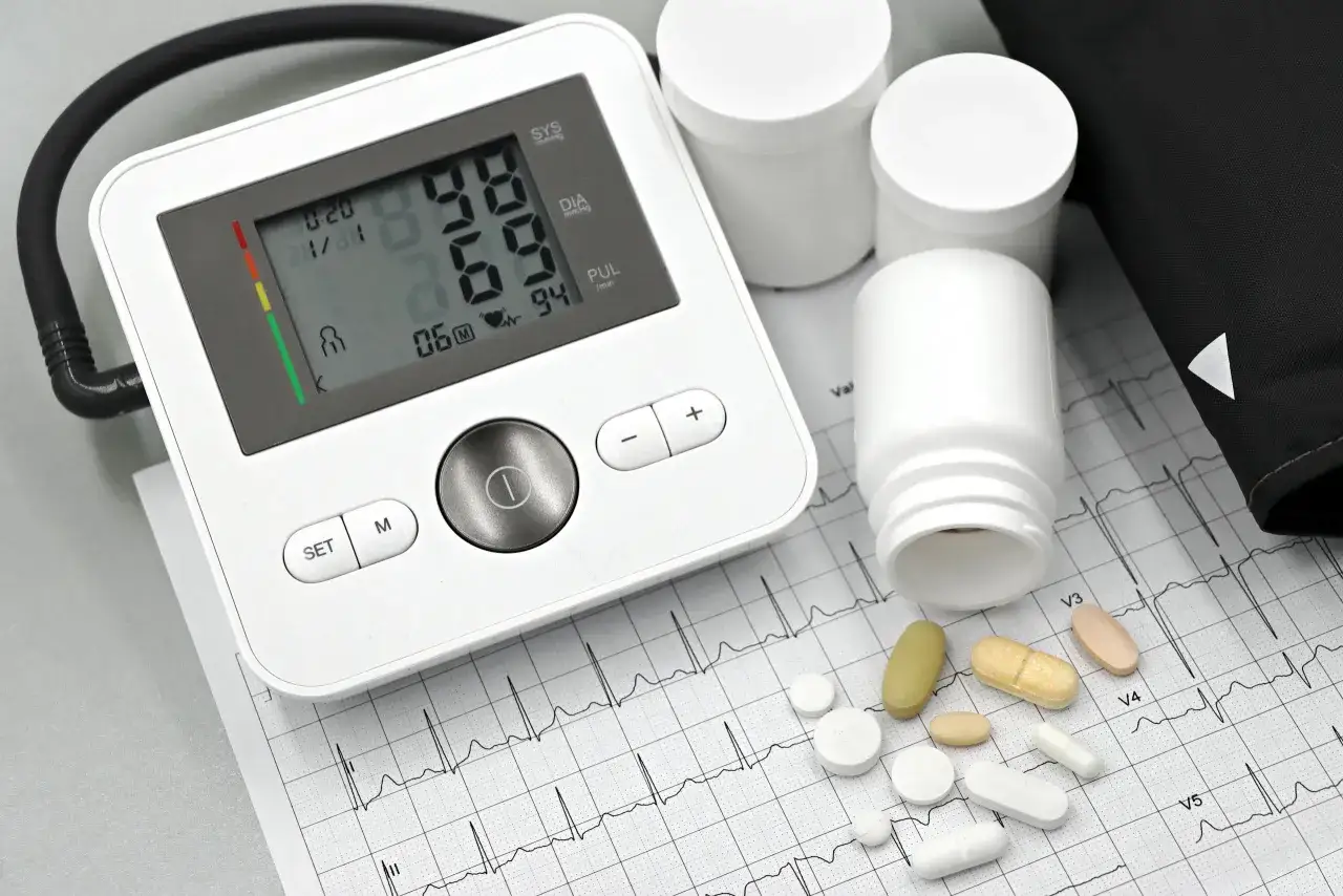 Blutdruckmessgerät, Pillendosen und Tabletten, darunter auch Telmisartan, liegen auf einem EKG-Streifen.