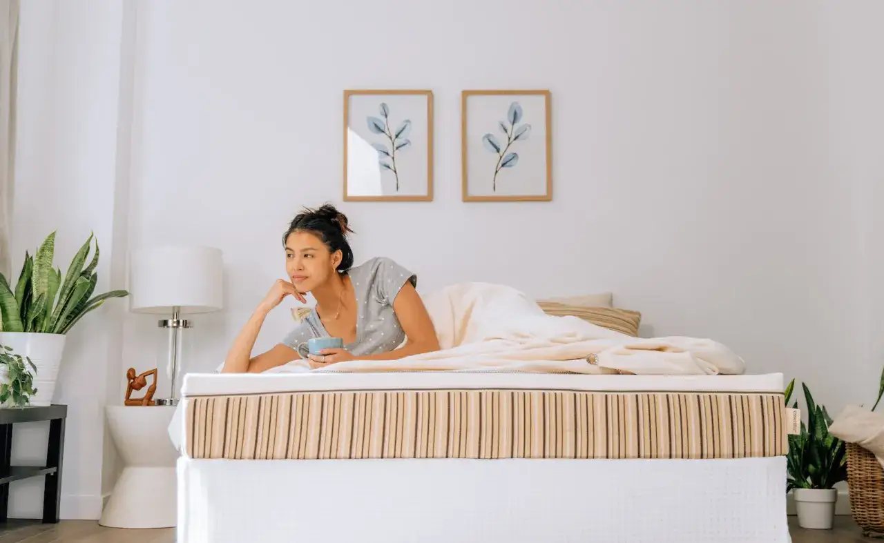 A woman enjoys a morning coffee in bed, resting on a mattress designed for athletes.
