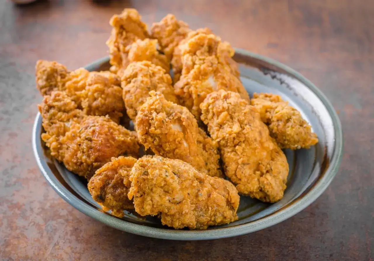 Piatto colmo di alette di pollo croccanti, cotte alla perfezione nella friggitrice ad aria.