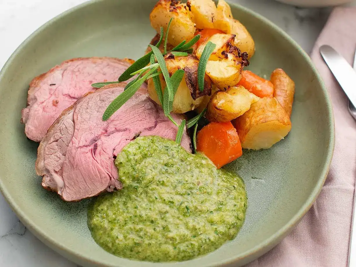Saftig lammstek med ben, serverad med rostade rotfrukter, örtsås och rosmarin. En klassisk svensk rätt.