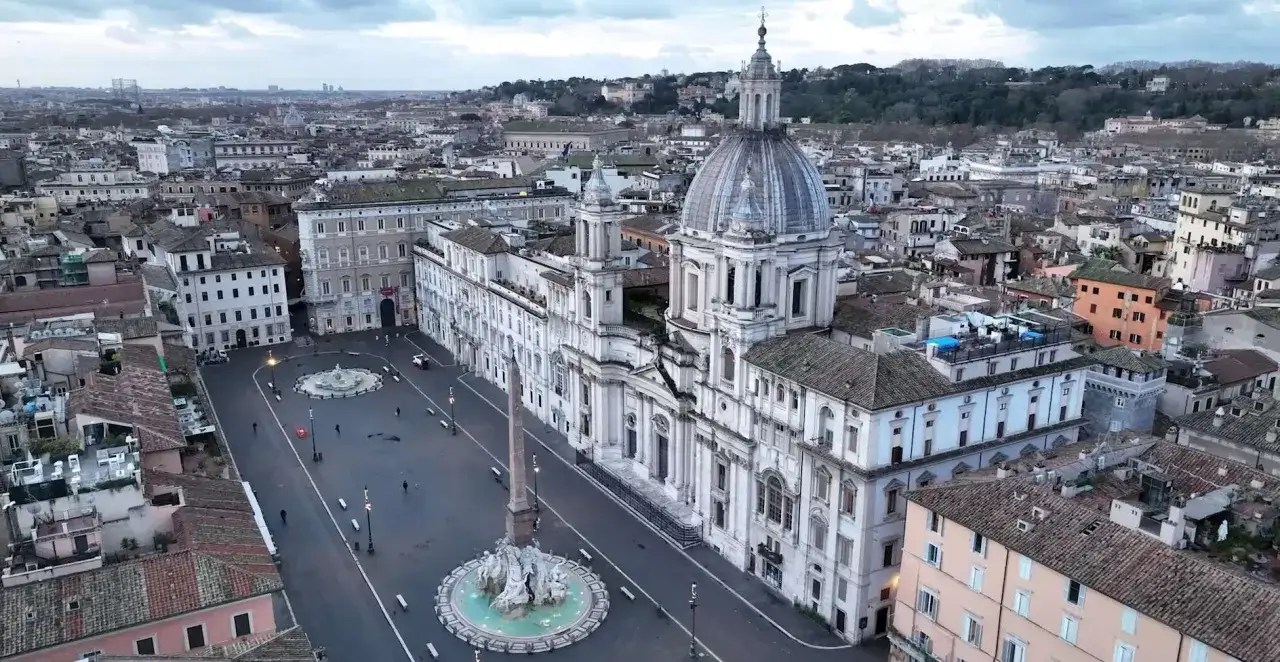 La maestosa chiesa di Piazza Navona domina la scena, con la sua cupola imponente e la facciata barocca. L'obelisco e la fontana completano il quadro di questa iconica piazza romana.