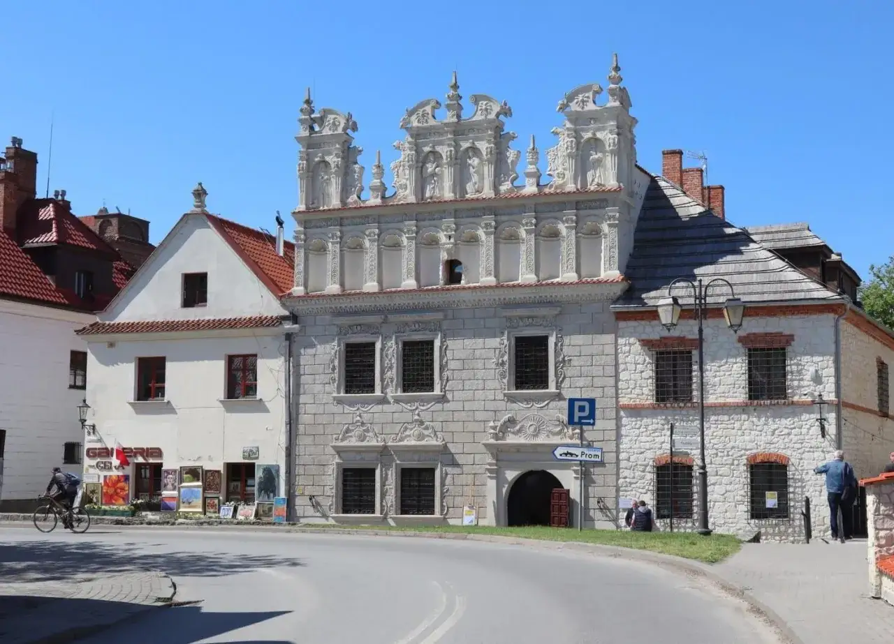 Bogata, zdobiona facjata renesansowej kamienicy w Sandomierzu. Obok galeria sztuki i uliczka.