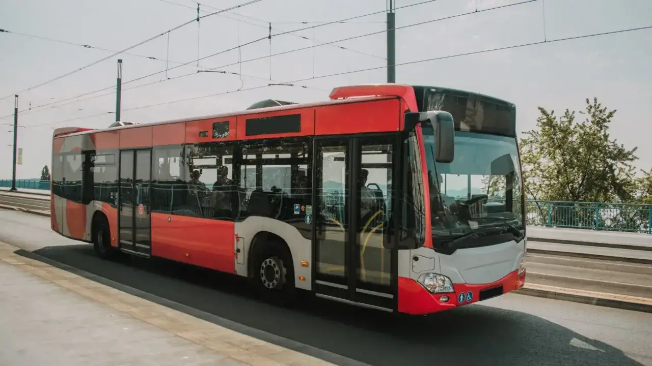 Czerwony autobus miejski jedzie po moście, kierując się nad morze.