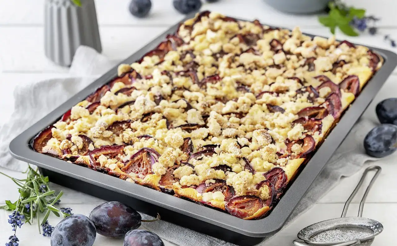 Frisch gebackener Zwetschgenkuchen mit Streuseln in einer rechteckigen Form. Saftige Pflaumen unter einer knusprigen Kruste.