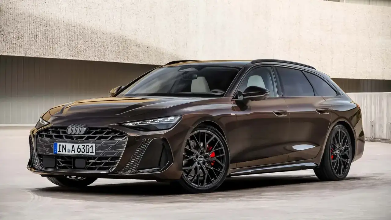 Elegancki brązowy Audi A6 C9 Avant z czarnymi felgami i czerwonymi zaciskami hamulcowymi, zaparkowany przed betonową ścianą.