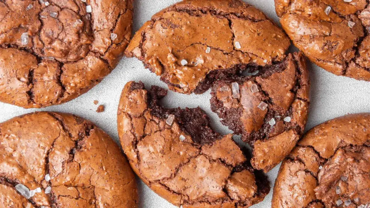 Saftige brownie cookies mit knackiger Kruste und grobem Meersalz bestreut. Einer ist zerbrochen und zeigt das feuchte Innere.