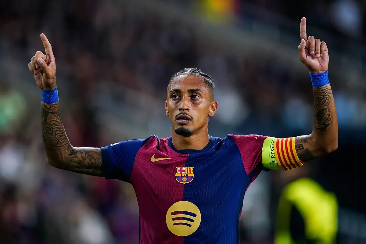 Raphinia, piłkarz FC Barcelony, świętuje bramkę, unosząc palce wskazujące do góry.