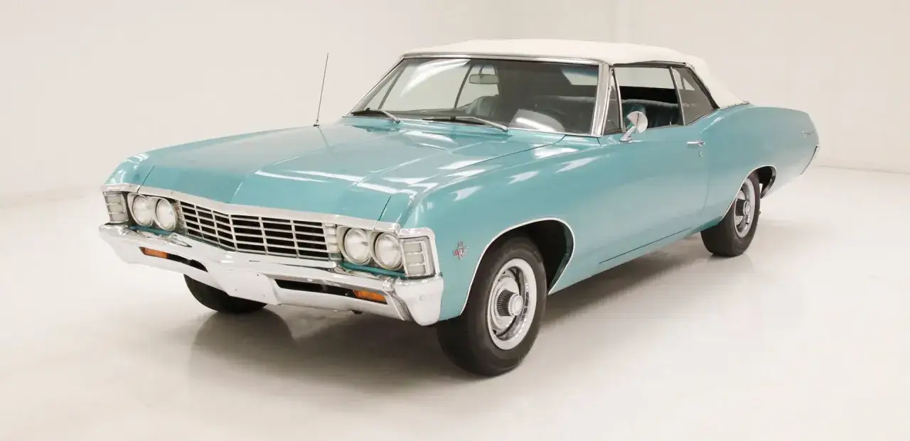 Błękitny kabriolet Chevrolet Impala 1967 z białym dachem, gotowy na letnią przejażdżkę.