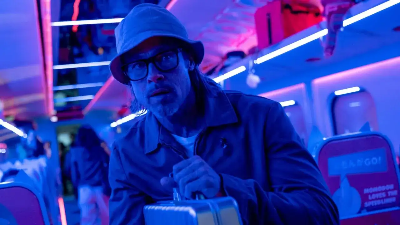 Brad Pitt con cappello e occhiali, su un treno ad alta velocità. Le recensioni di Bullet Train lo descrivono come un'avventura adrenalinica.