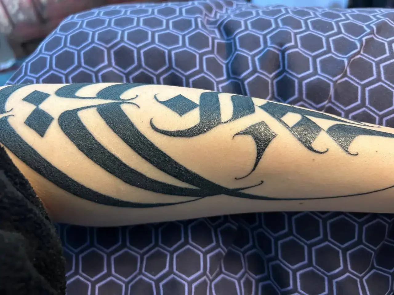 Un bras orné d'un tatouage calligraphique noir. La peau semble lisse, signe que le tatouage est cicatrisé.