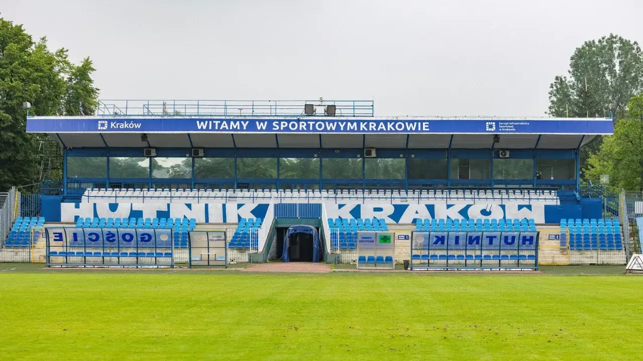 Stadion Hutnik Krak&oacute;w z niebieskimi siedzeniami i napisem 