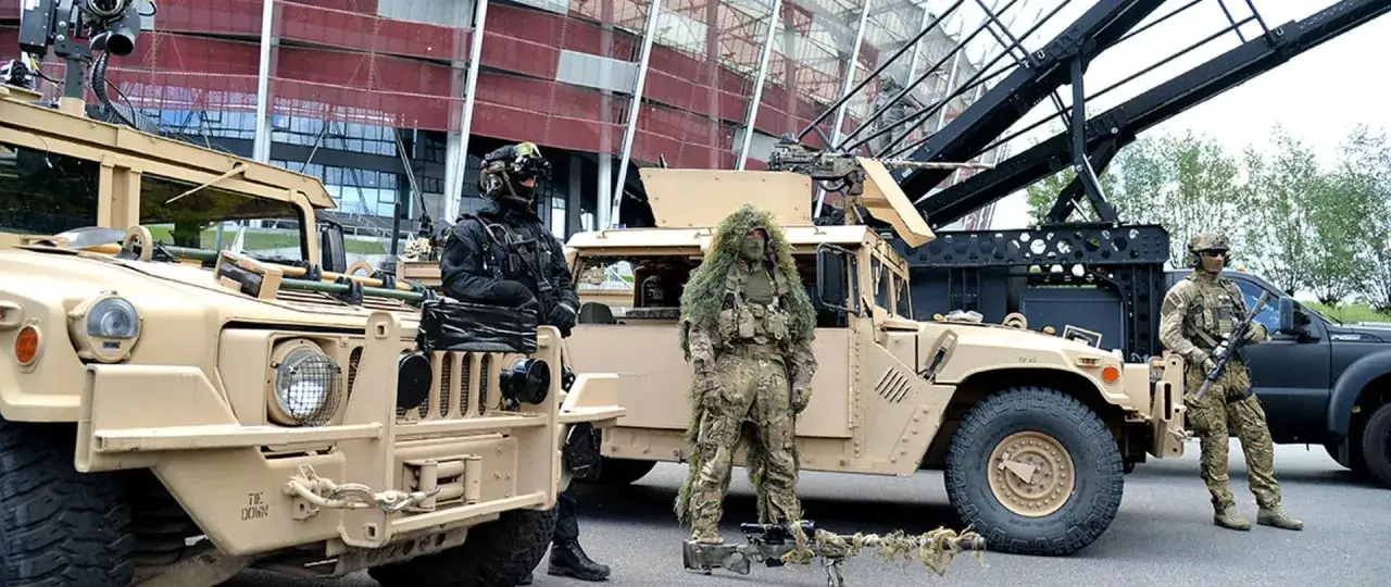 Żołnierze w kamuflażu i oporządzeniu, obok pojazdów wojskowych. Sprzęt spełnia **standard militarny mil-std-810h**.