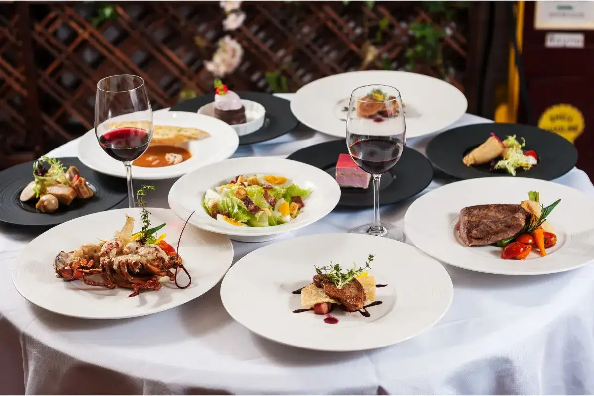 Un festin de produits du terroir : homard, steak, salade c&eacute;sar, foie gras, et plus encore, accompagn&eacute;s de vin rouge.
