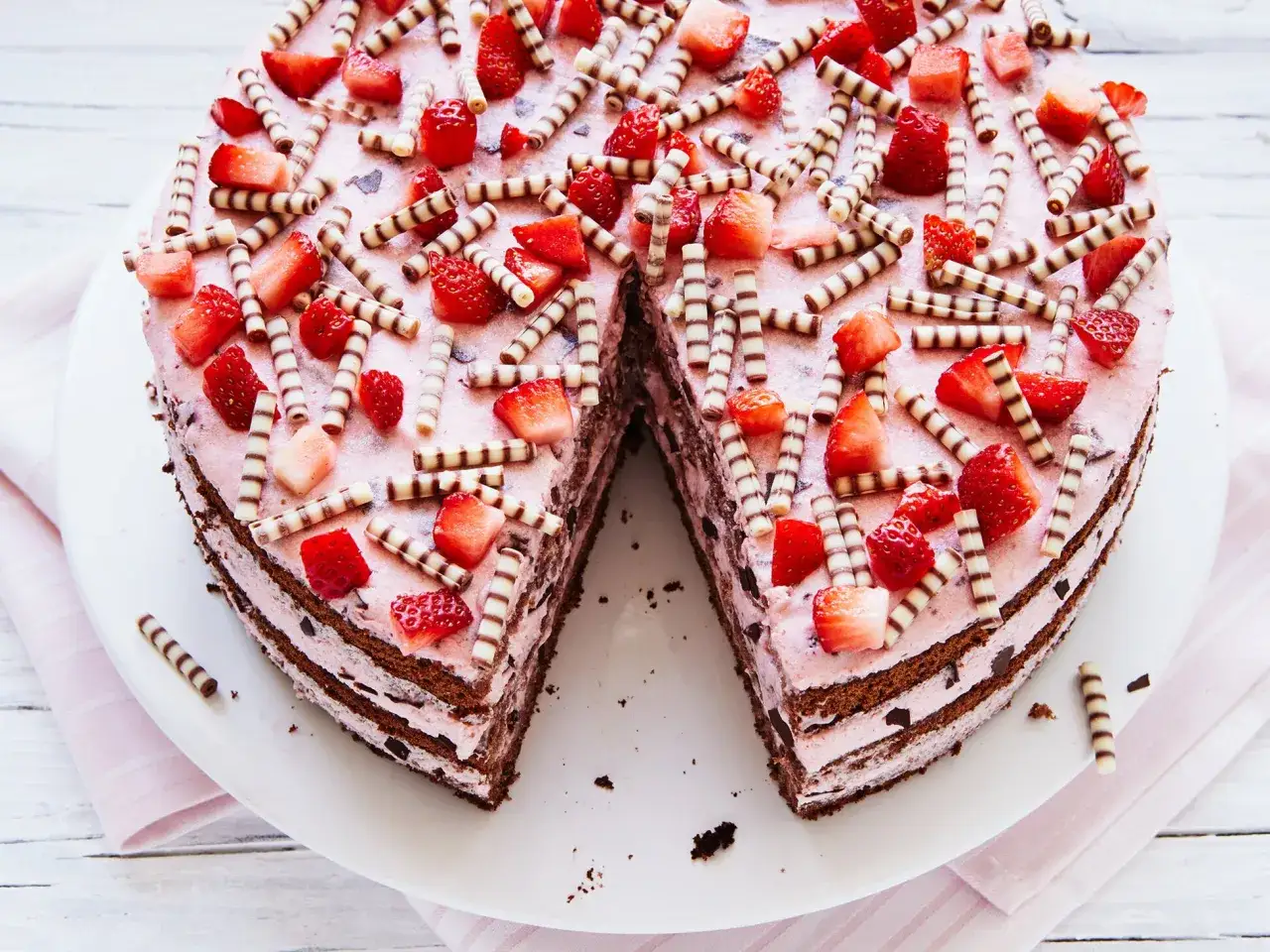 Eine k&ouml;stliche Erdbeer Stracciatella Torte, dekoriert mit frischen Erdbeeren und Schokor&ouml;llchen, wartet darauf, angeschnitten zu werden.
